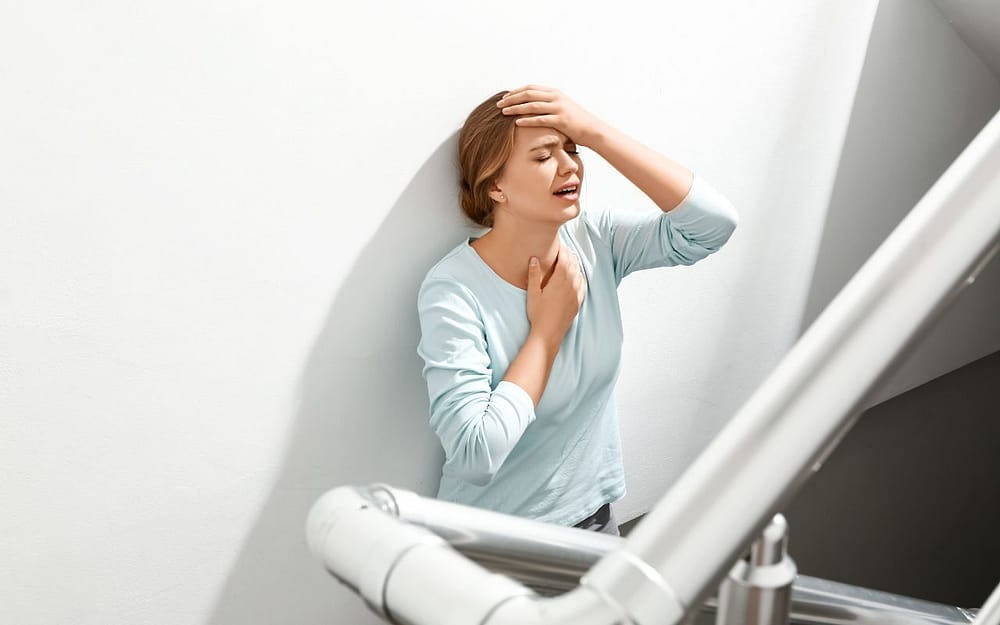 A woman is leaning on a stair with her hand on her chest - signs-of-dental-anxiety-panic-attack