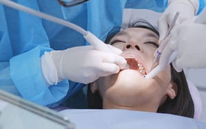 A woman seeks dental examination to understand the cause of her bleeding gums possibly due to periodontitis or gum disease.