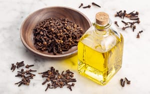 A bowl of cloves, known for their toothache remedies that work, placed near a bottle of olive oil.