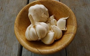 Home remedy for toothaches: Garlic in a wooden bowl on a wooden table.