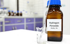 A home remedy for toothache, hydrogen peroxide, next to a glass of water.
