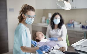 A dental hygienist is examining a patient in a dental office.