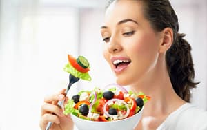 A woman is eating a bowl of salad before braces.
