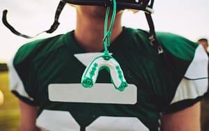 A football player with a toothpick-embellished helmet pondering what to do about a knocked-out tooth.