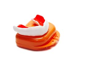 A sports mouthguard, featuring orange and white colors, displayed on a white background.