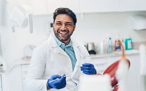 A smiling man celebrating National Dentists Day in a dentist's office.